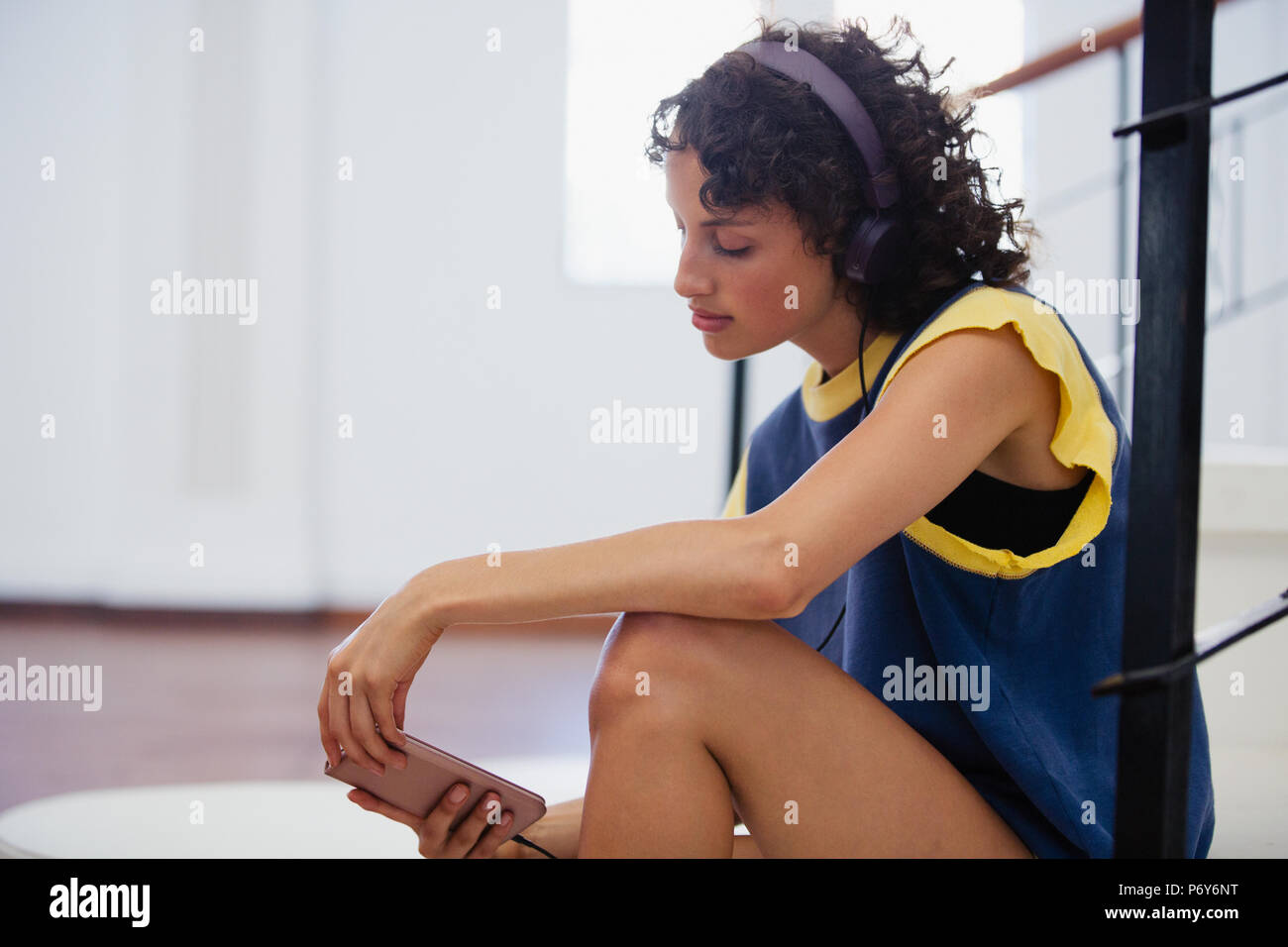 Young female dancer listening to music with headphones and mp3 player in dance studio Stock Photo