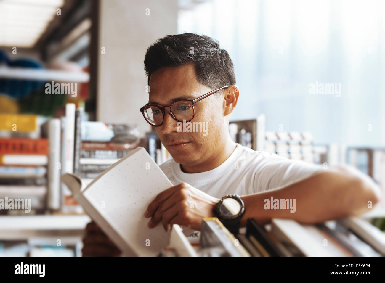 Young man reading book in a book store. Stock Photo