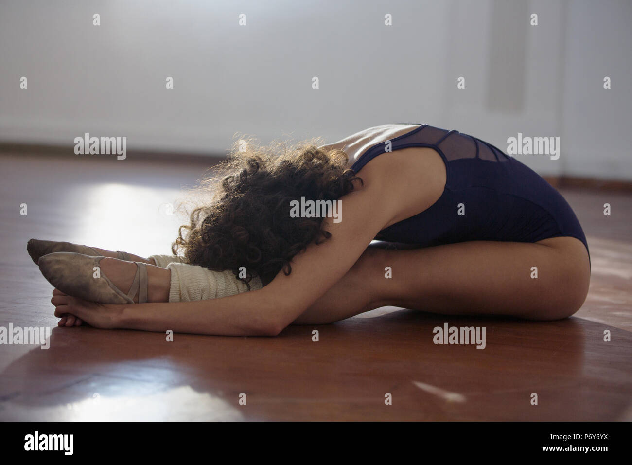 Young female dancer stretching in forward fold in dance studio Stock Photo