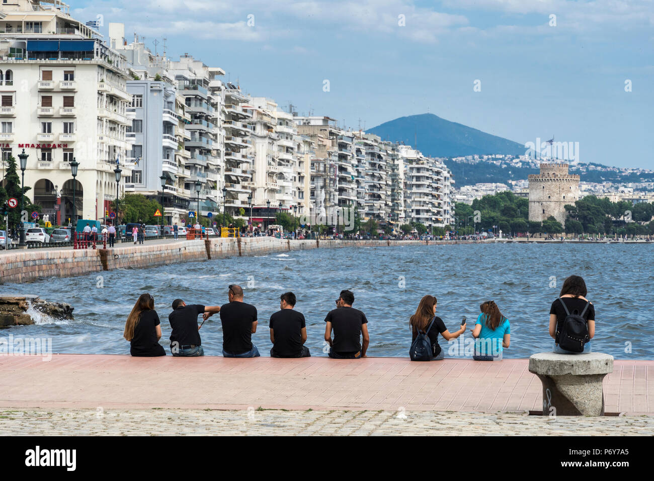 People relaxing on Thessaloniki waterfront with apartment blocks on