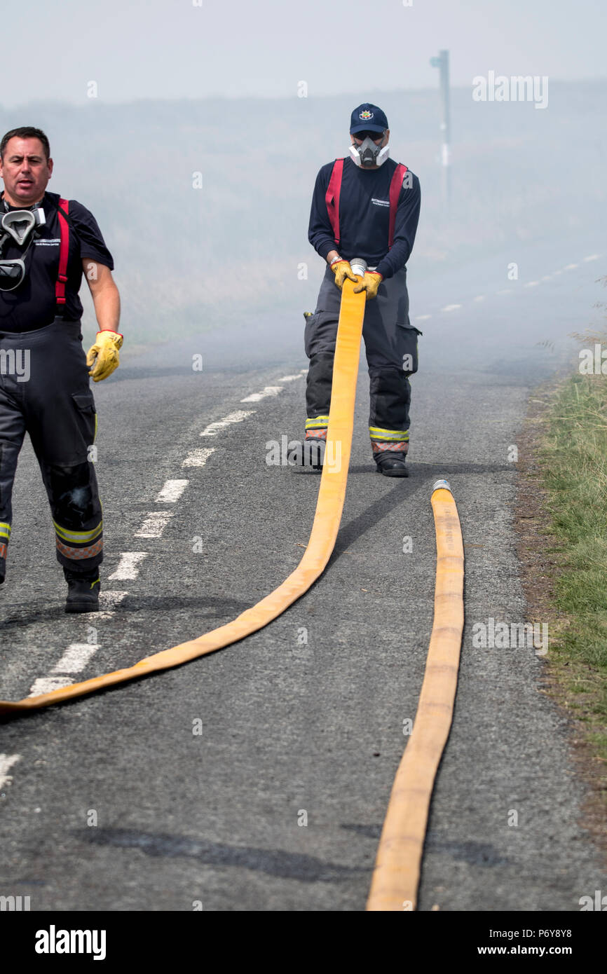 1 July 2018 Firefighters drag heavy hoses across the road on Winter Hill before battling the