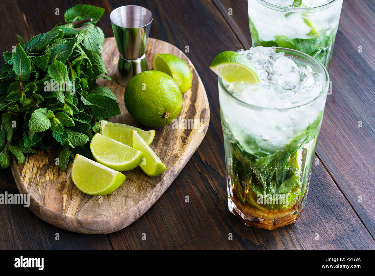 Dirty mojito and ingredients (fresh mint, sliced lime) served on a dark wooden board. High resolution. Stock Photo