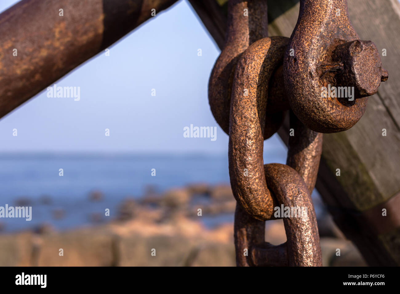 Strong forged rusty chain and nail in front of seascape Stock Photo