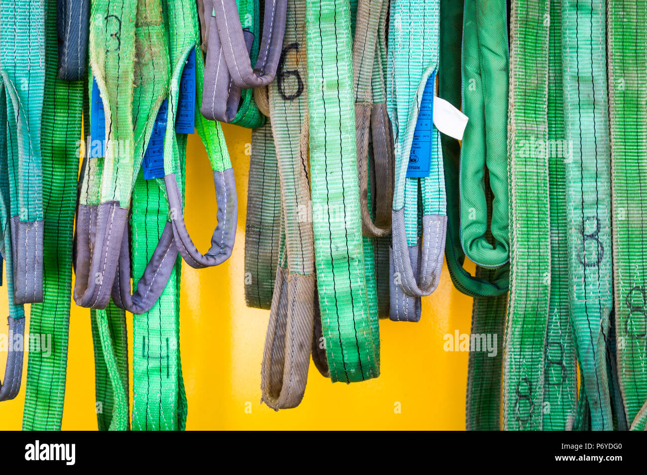 Worn numbered green ropes hanging in different lenghts on yellow ...