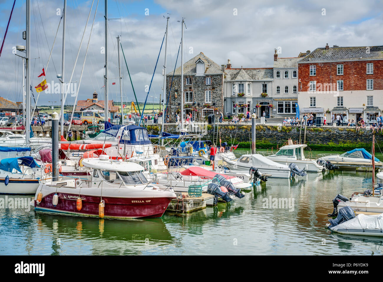 This is a harbour scene taken at Padstow, Cornwall, England showing a view of different boats moored in the marina with a backdrop of old buildings. Stock Photo