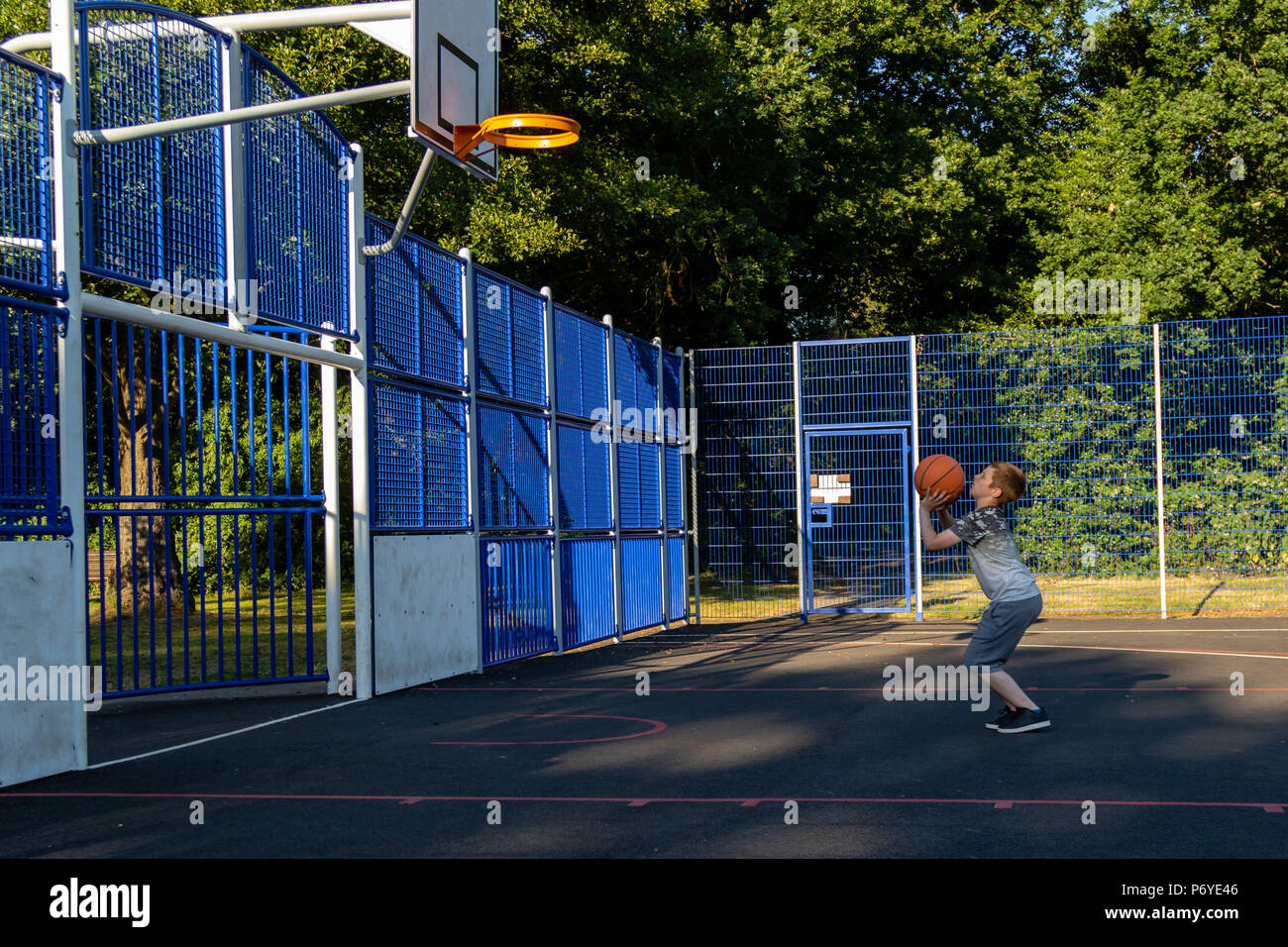 Pre-teen boy shooting basket ball in a park Stock Photo