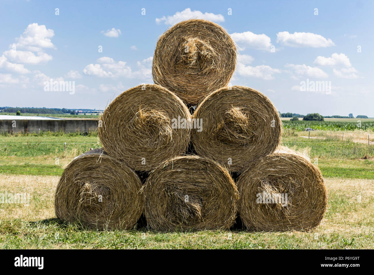 Stacked like a pyramid, round yellow bales of straw in sunny weather