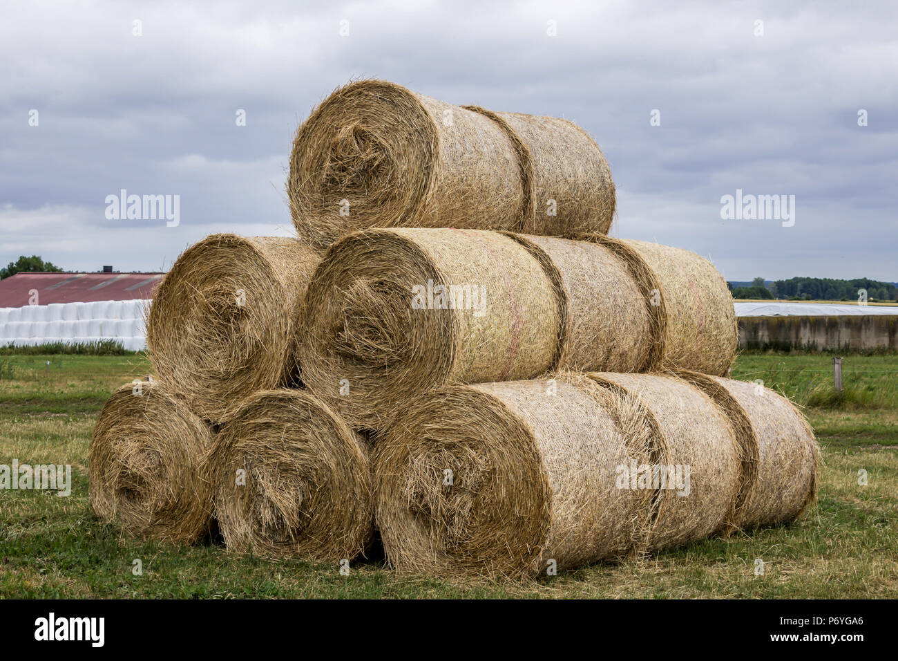 Stacked like a pyramid, round yellow bales of straw in the cloudy