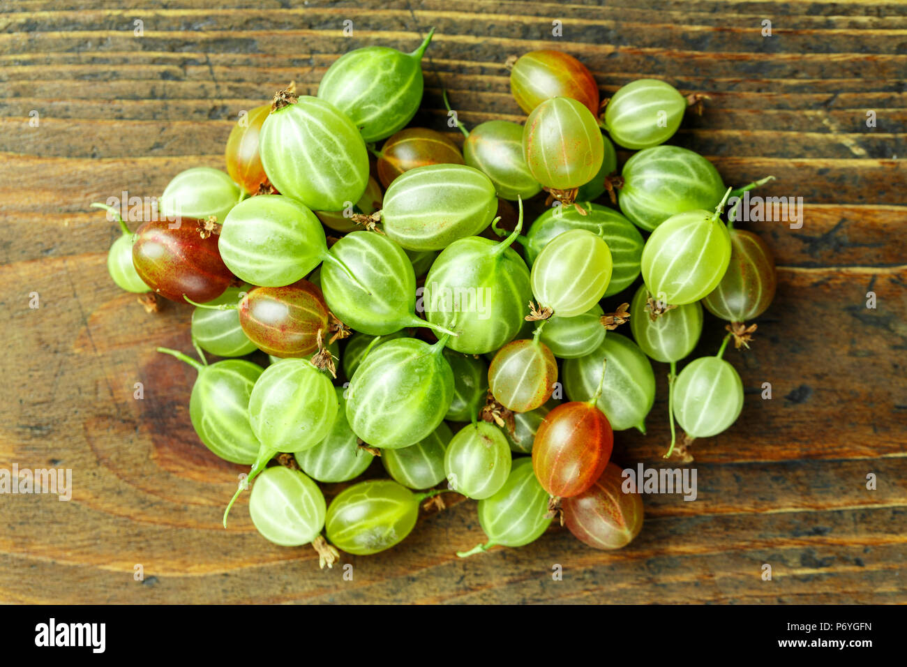 ripe gooseberry close-up scattered on a wooden background Stock Photo ...