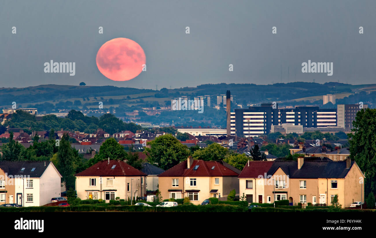 sunny weather clear skies as a Strawberry hot or mead moon or rose moon a full moon appears over yorkhill hospital Cathkin braes and Dechmont hill Stock Photo
