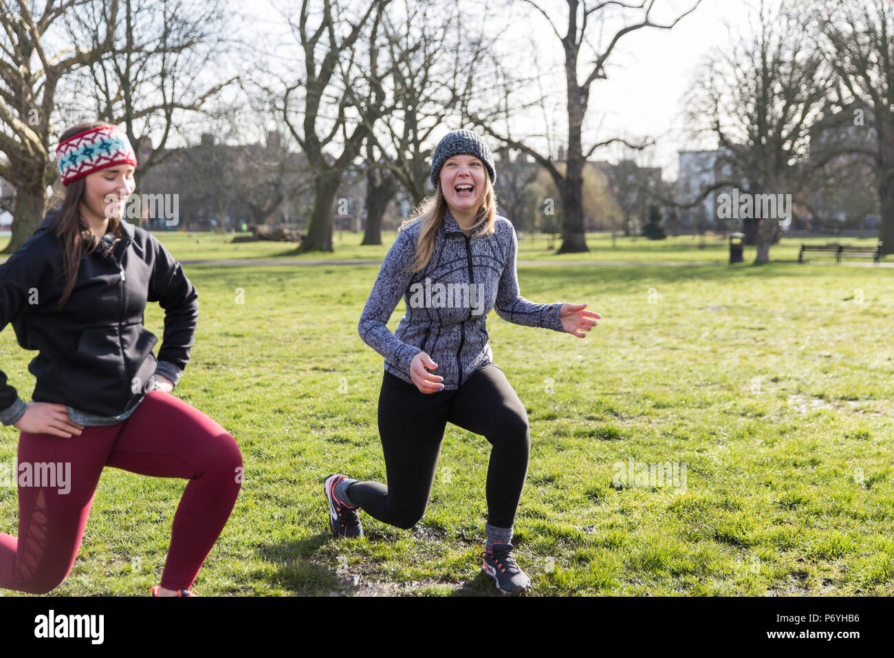 Smiling, confident women doing lunges in sunny park Stock Photo