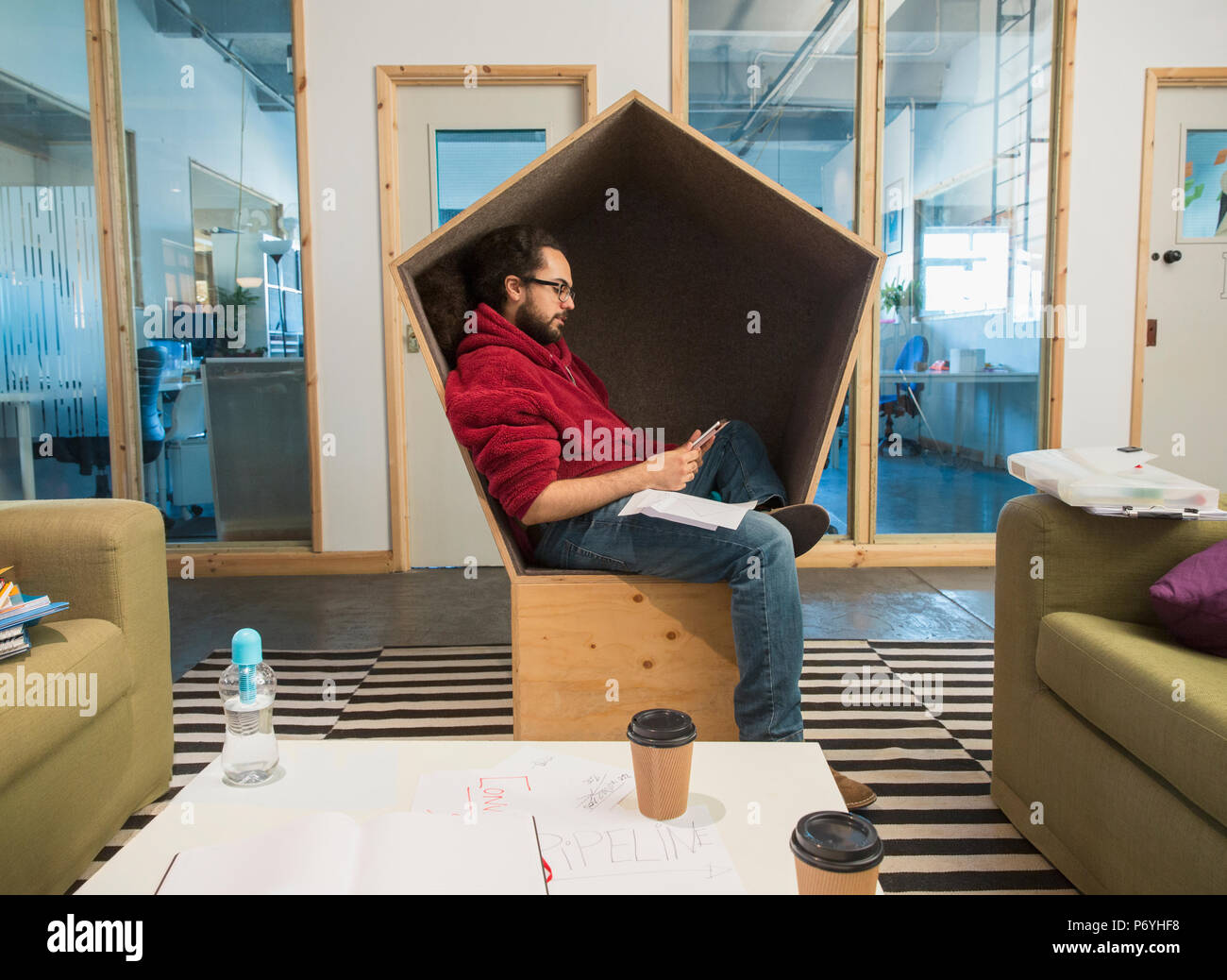 Creative businessman using smart phone in office cubby Stock Photo
