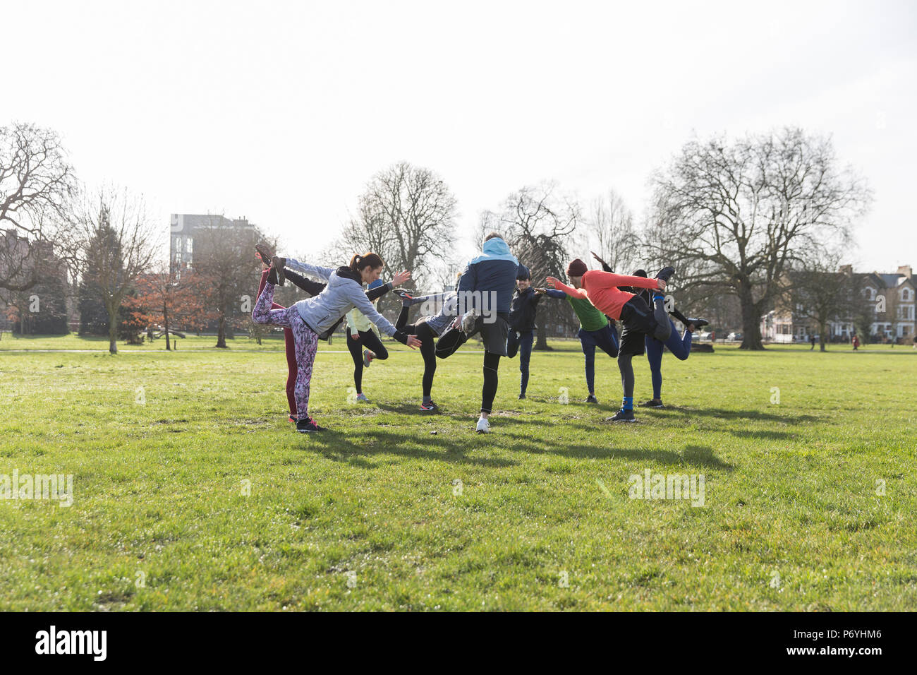 People exercising, stretching in sunny park Stock Photo