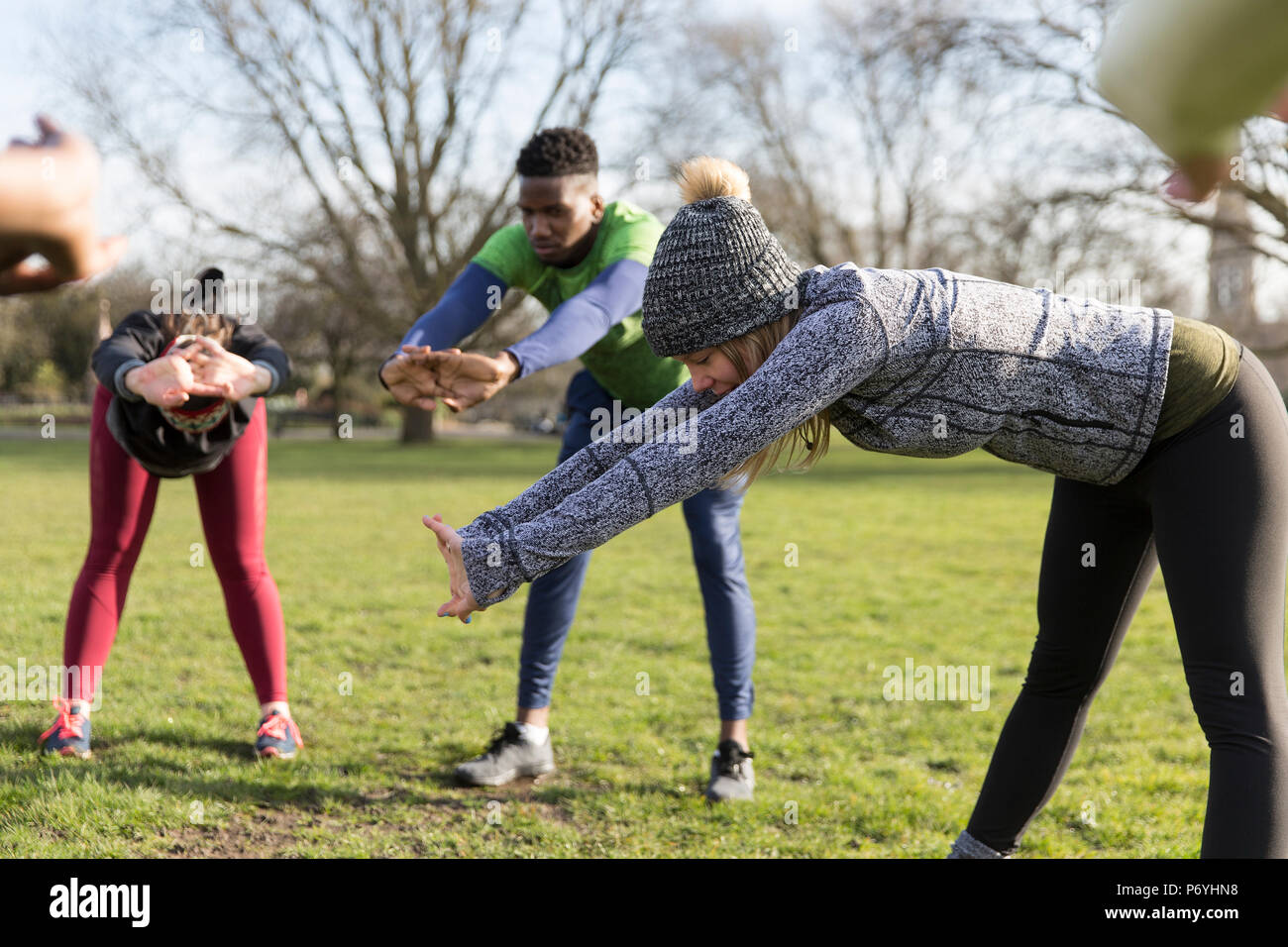 People exercising, stretching in sunny park Stock Photo