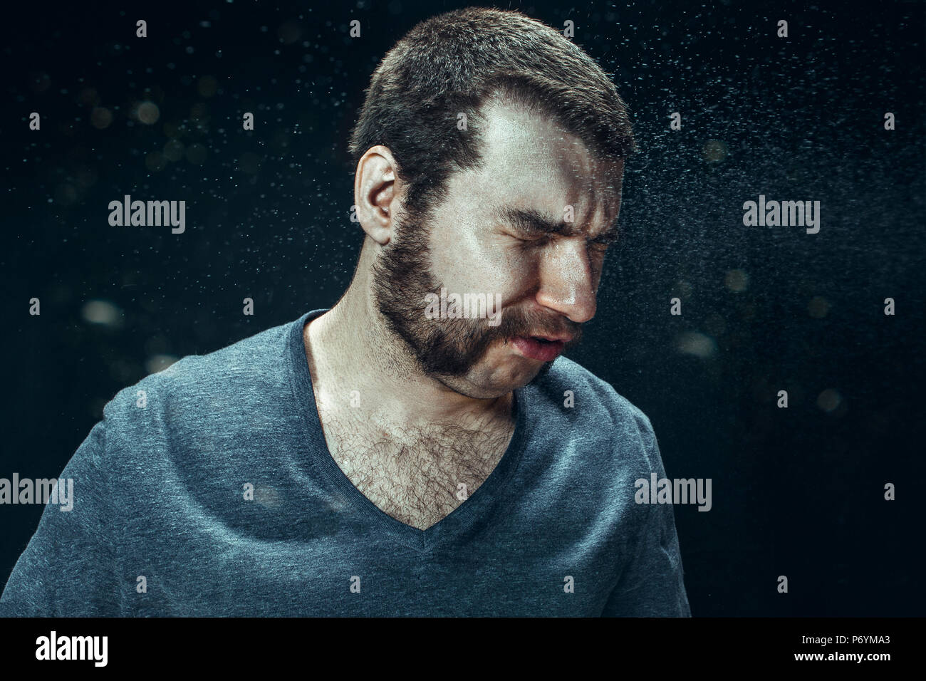 Young handsome man with beard sneezing, studio portrait Stock Photo