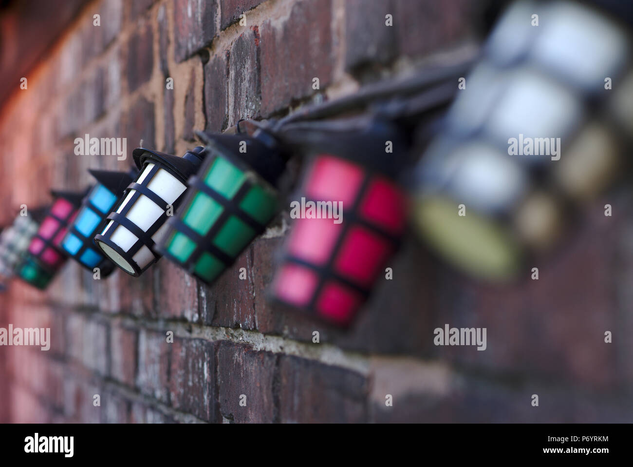 String of coloured lights against a brick wall Stock Photo