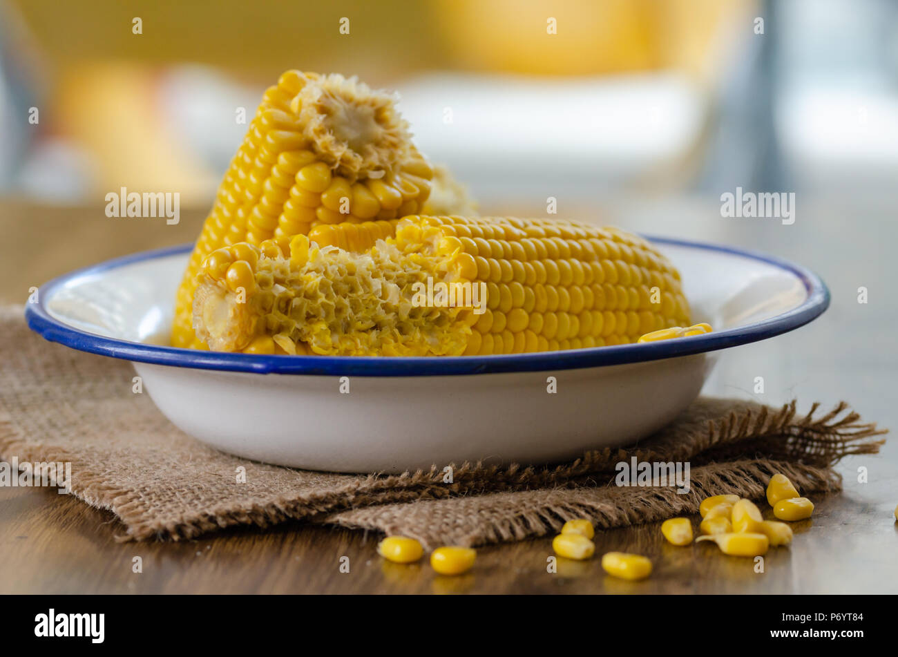 Cooked corncobs in white dish on rustic napkin.Ready to eat and half-eaten corn cob Stock Photo