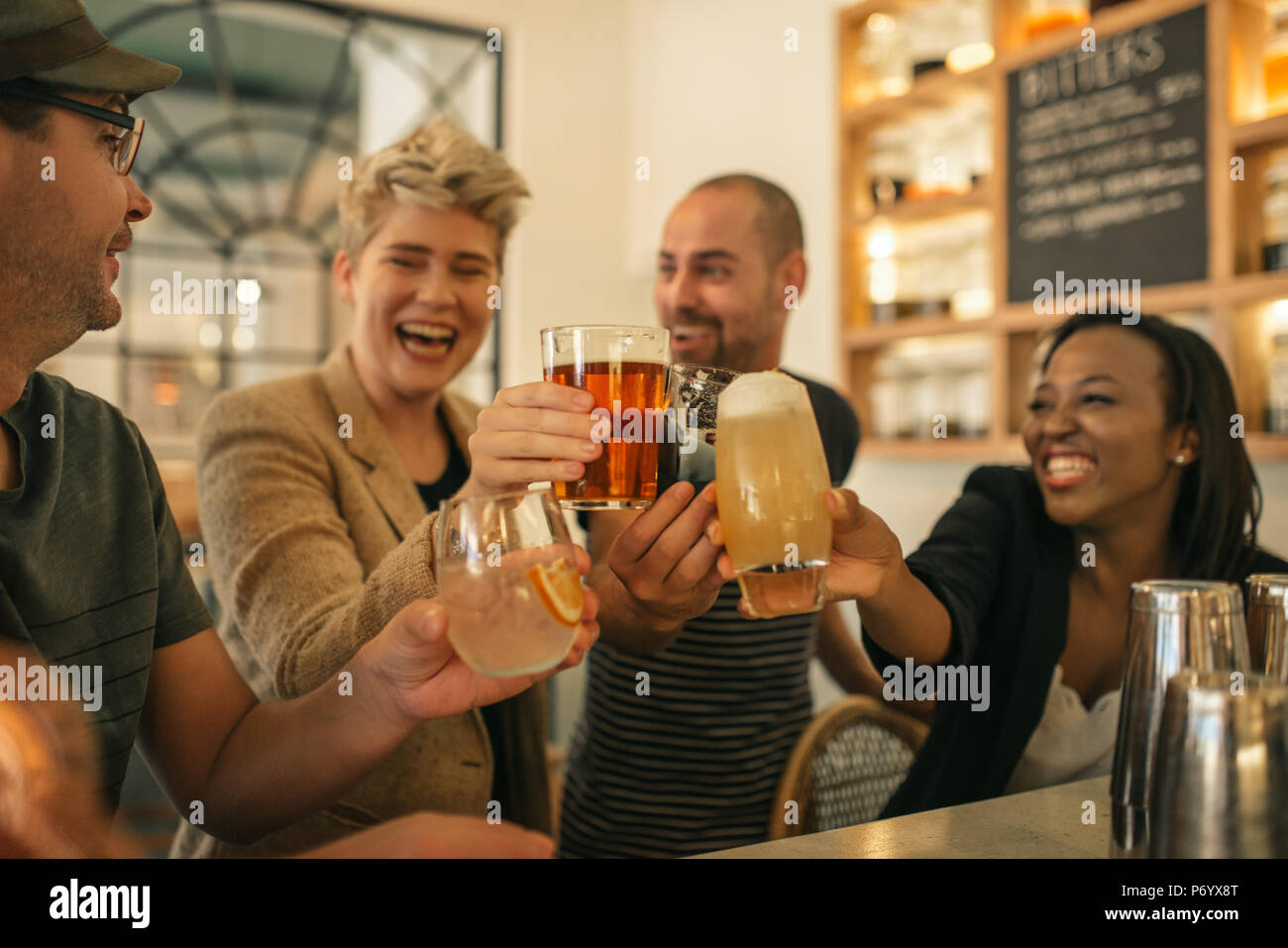 Friends hanging out together in a bar cheering with drinks  Stock Photo