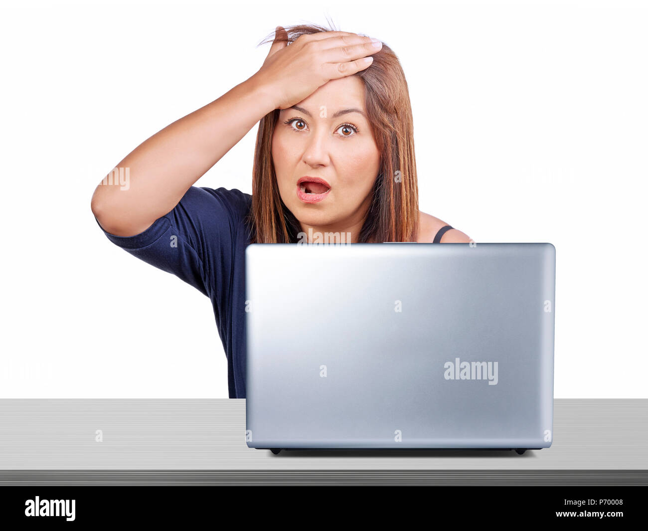 Worried woman working at desk with laptop gesturing forgotten something or regret for mistake isolated Stock Photo