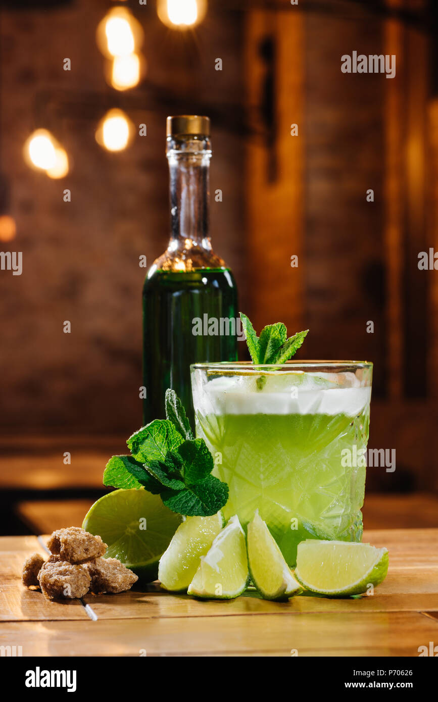 close-up view of green van gogh cocktail in glass with bottle of absinthe on wooden table Stock Photo