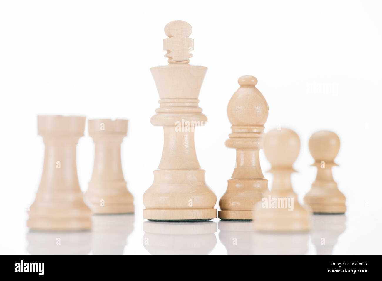 white wooden chess figures on white reflecting surface Stock Photo