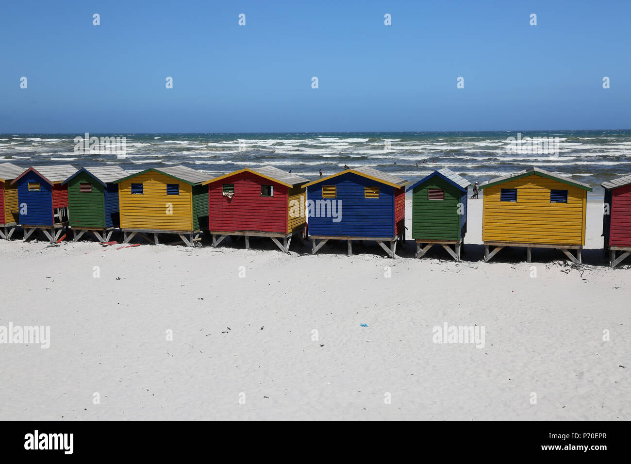 colourful beach huts on muizenburg beach with surf waves in background Stock Photo