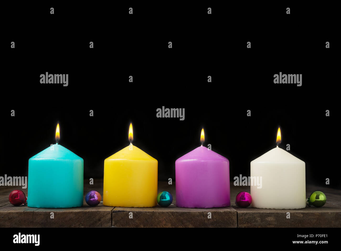 Multicolored burning candles with decorative  small balls on black background.Concept of New Year and Xmas Stock Photo