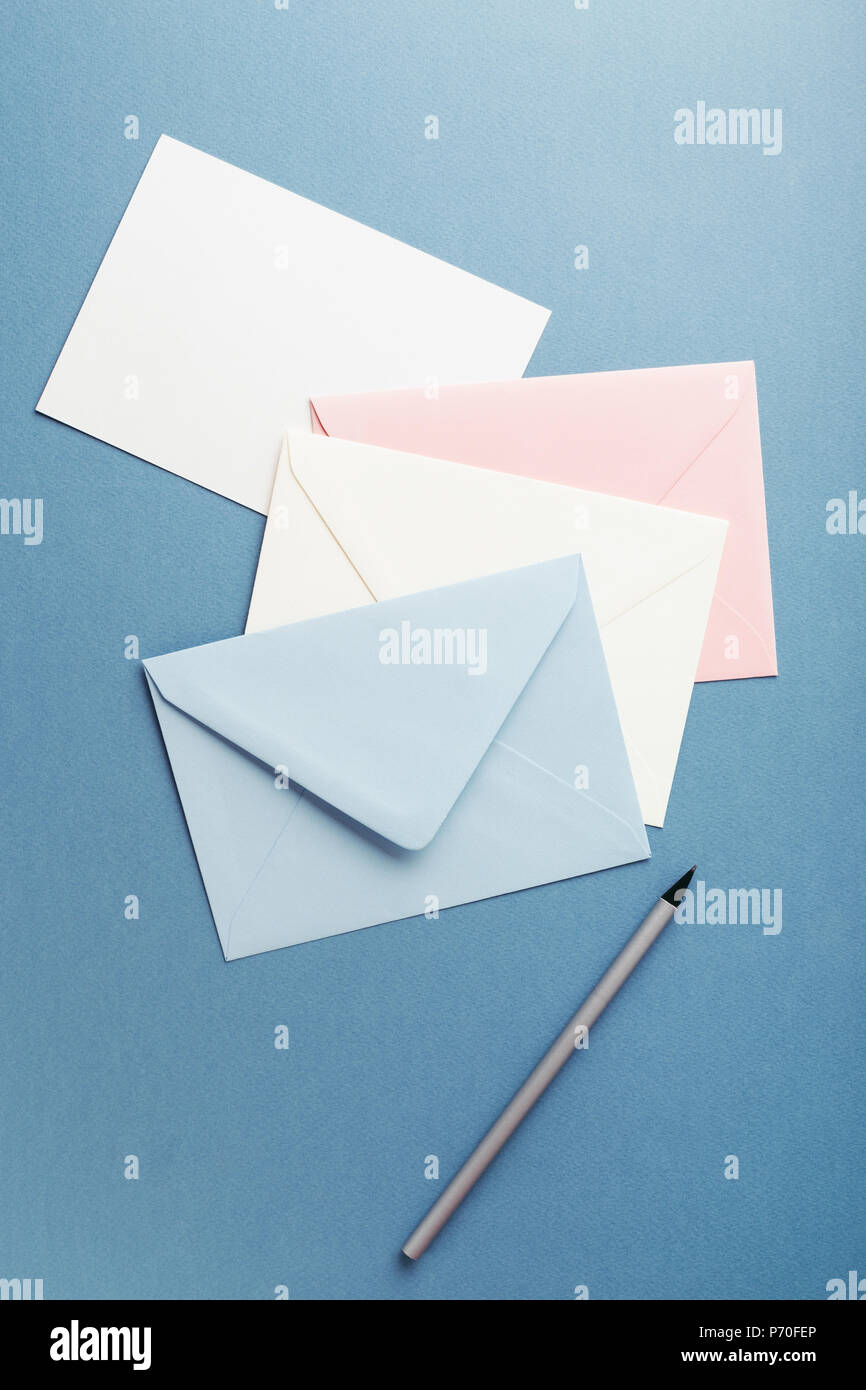 Group of colorful envelopes on blue table with empty card. Correspondence concept. Mockup. Stock Photo
