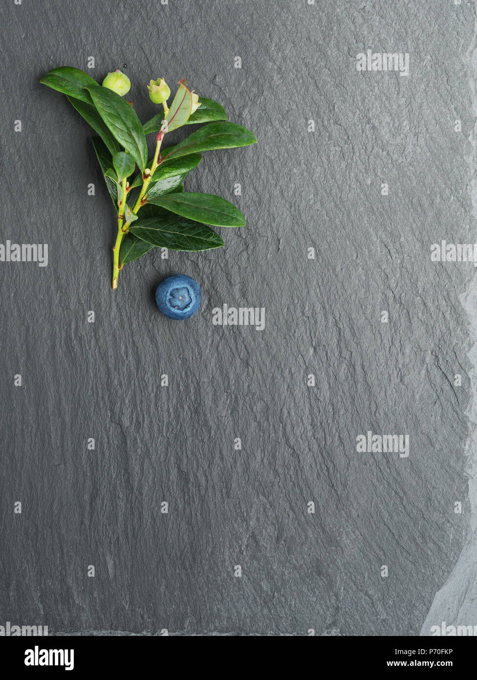 Fresh Blueberry with leaves on dark stone background. Flat lay, top view. Stock Photo
