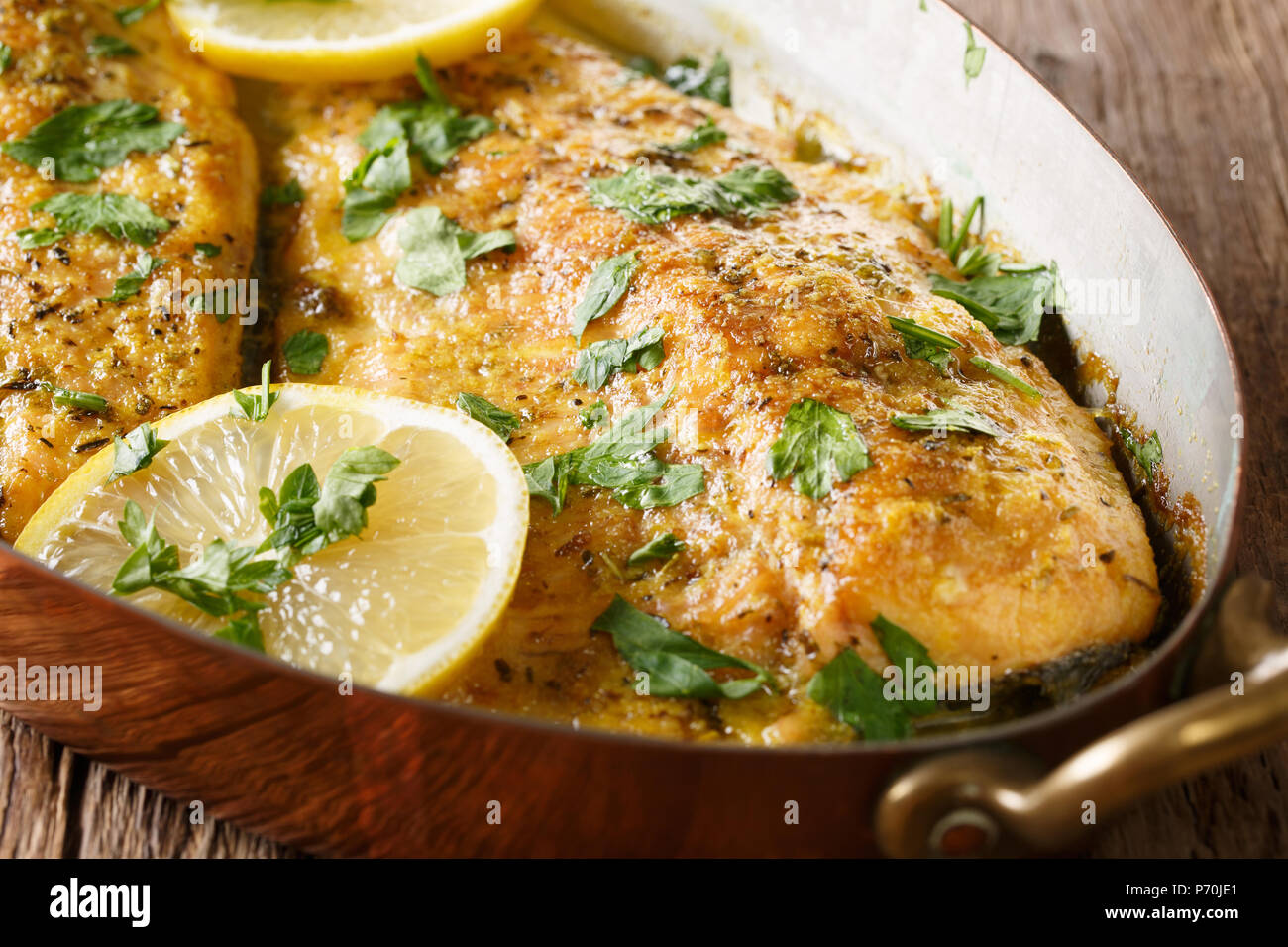 Delicious food trout fish with garlic lemon butter sauce, parsley closeup in a copper frying