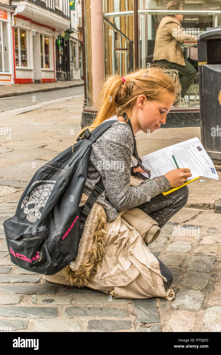 Young foreign exchange student filling in a questionnaire for a trip in the street in Canterbury, Kent, England, UK. Stock Photo