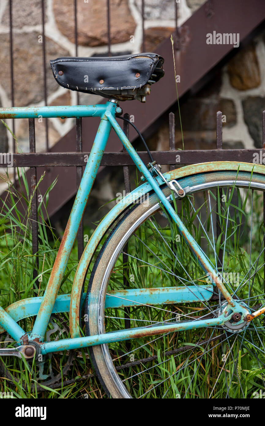 Closeup of a bicycle wheel and seat leaning on a rusty fence. Stock Photo