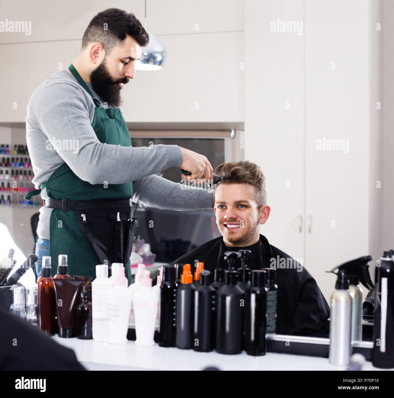 Young Spanish Male Hairdresser Doing Haircut For Male Client At