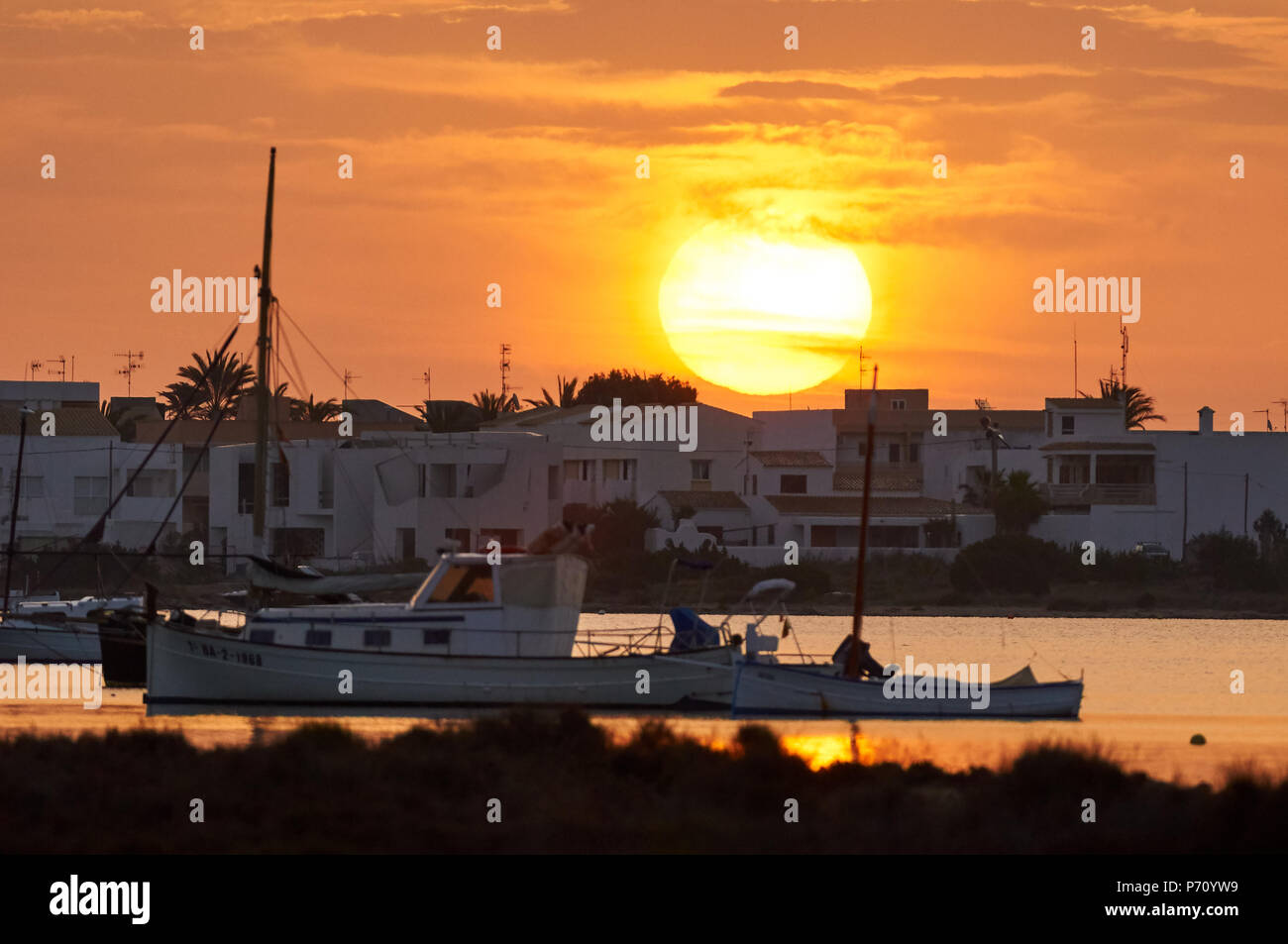 Traditional boat, llaüt, and other boats in Estany des Peix marine lagoon with the sunrise in Ses Salines Natural Park (Formentera, Balearic Islands) Stock Photo
