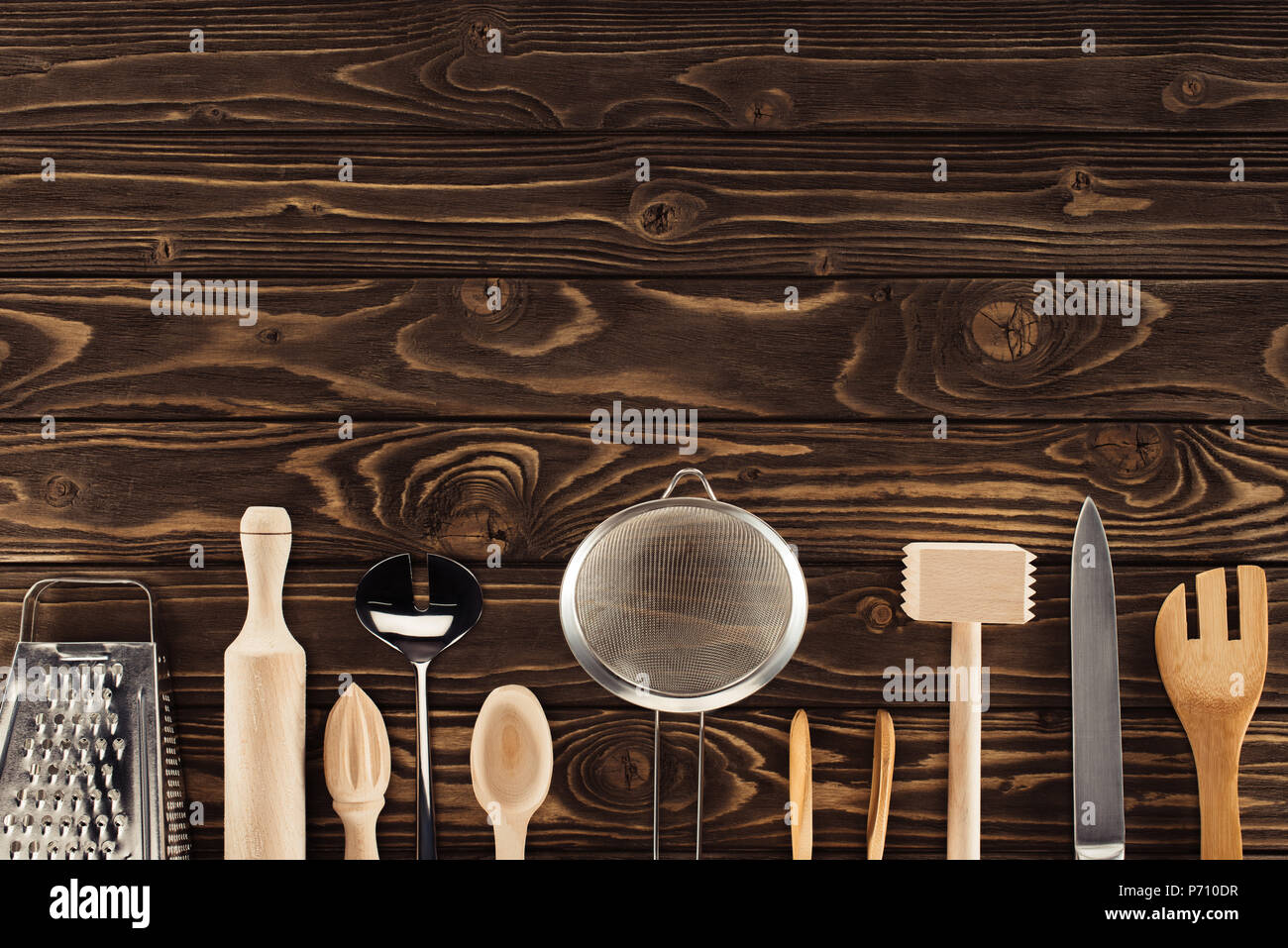 elevated view of kitchen utensils placed in row on wooden table Stock Photo
