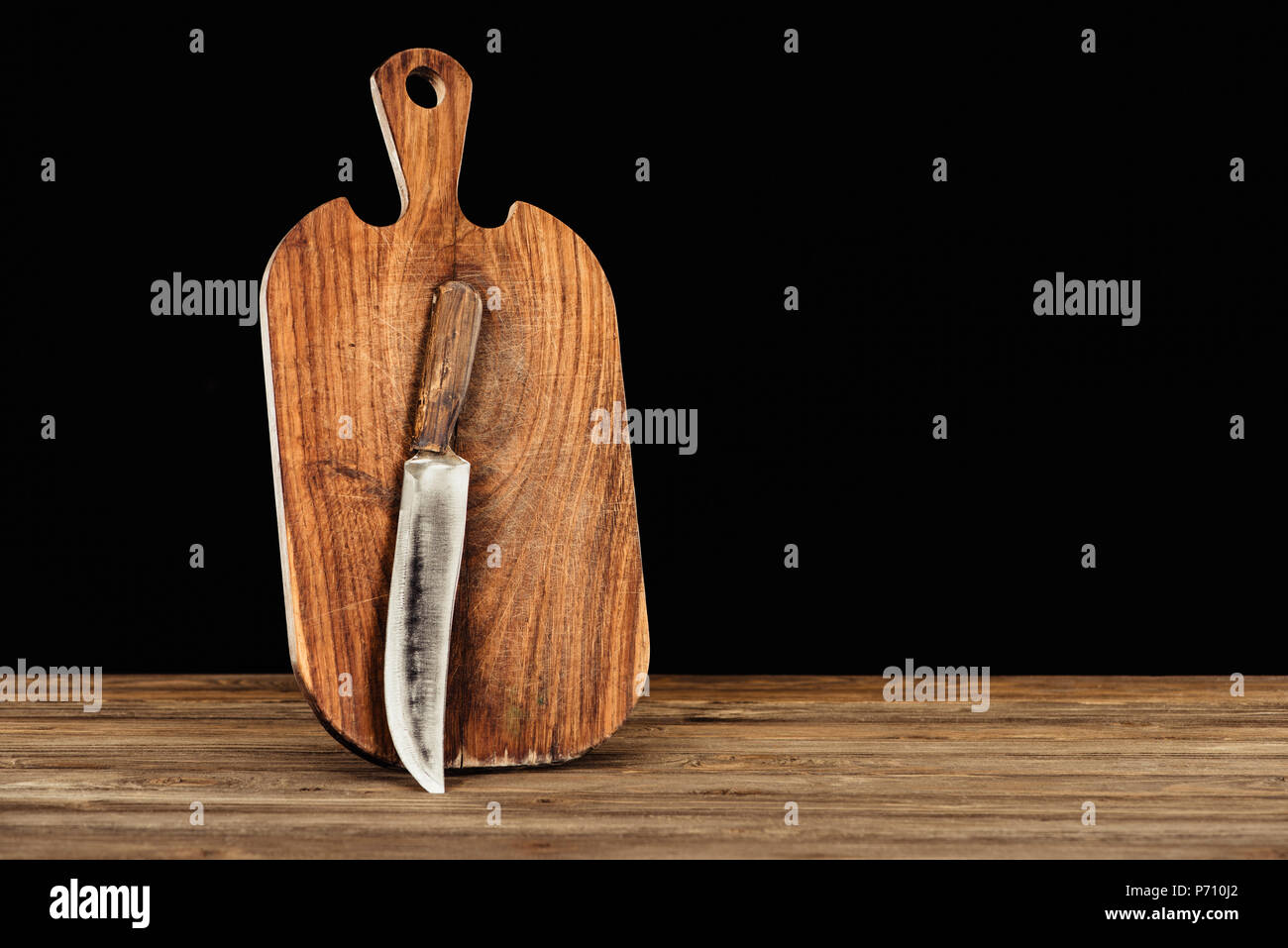 closeup view of knife and wooden cutting board on black background ...