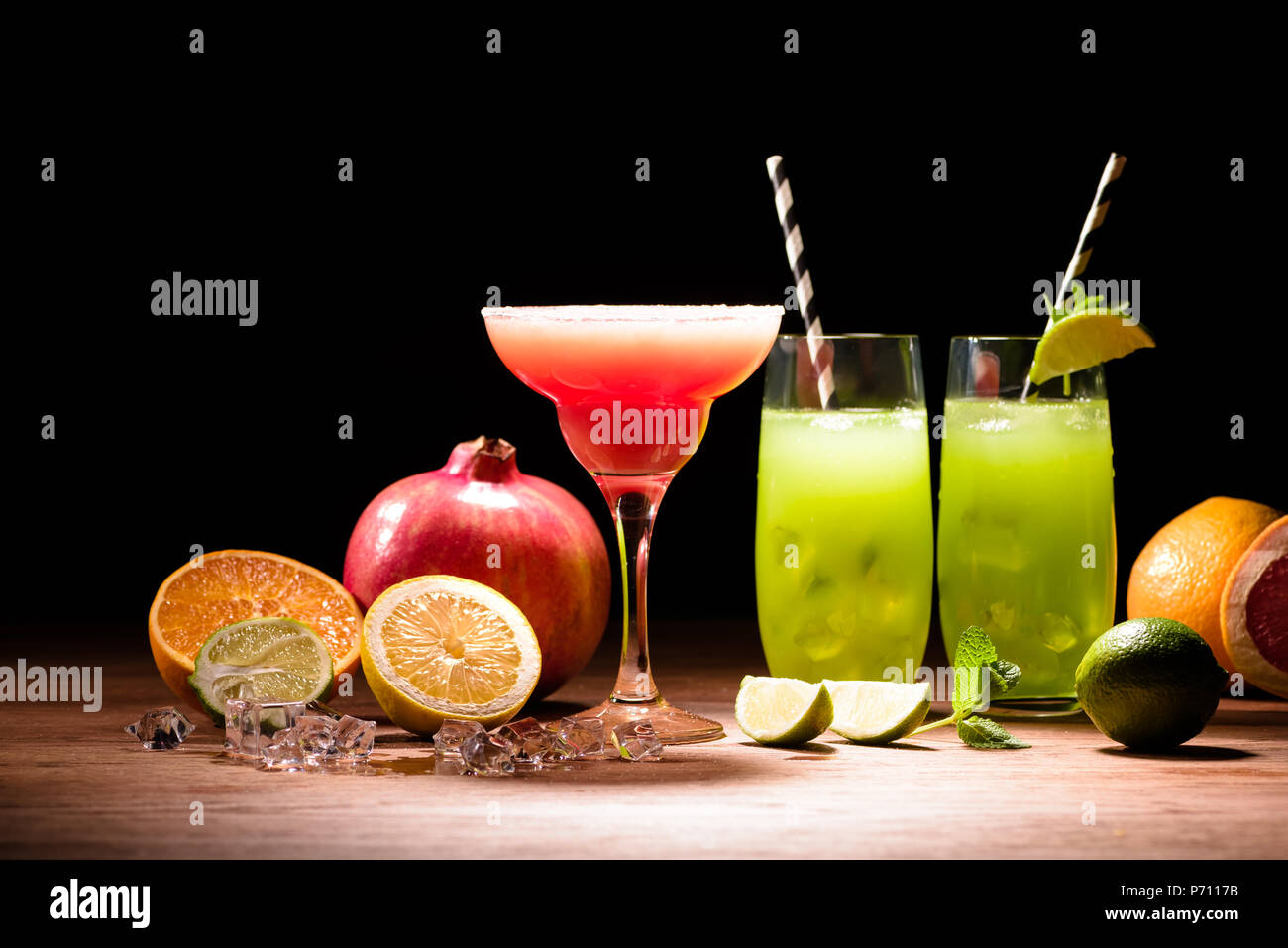 alcohol drinks with lime, pomegranate and ice cubes on table Stock Photo