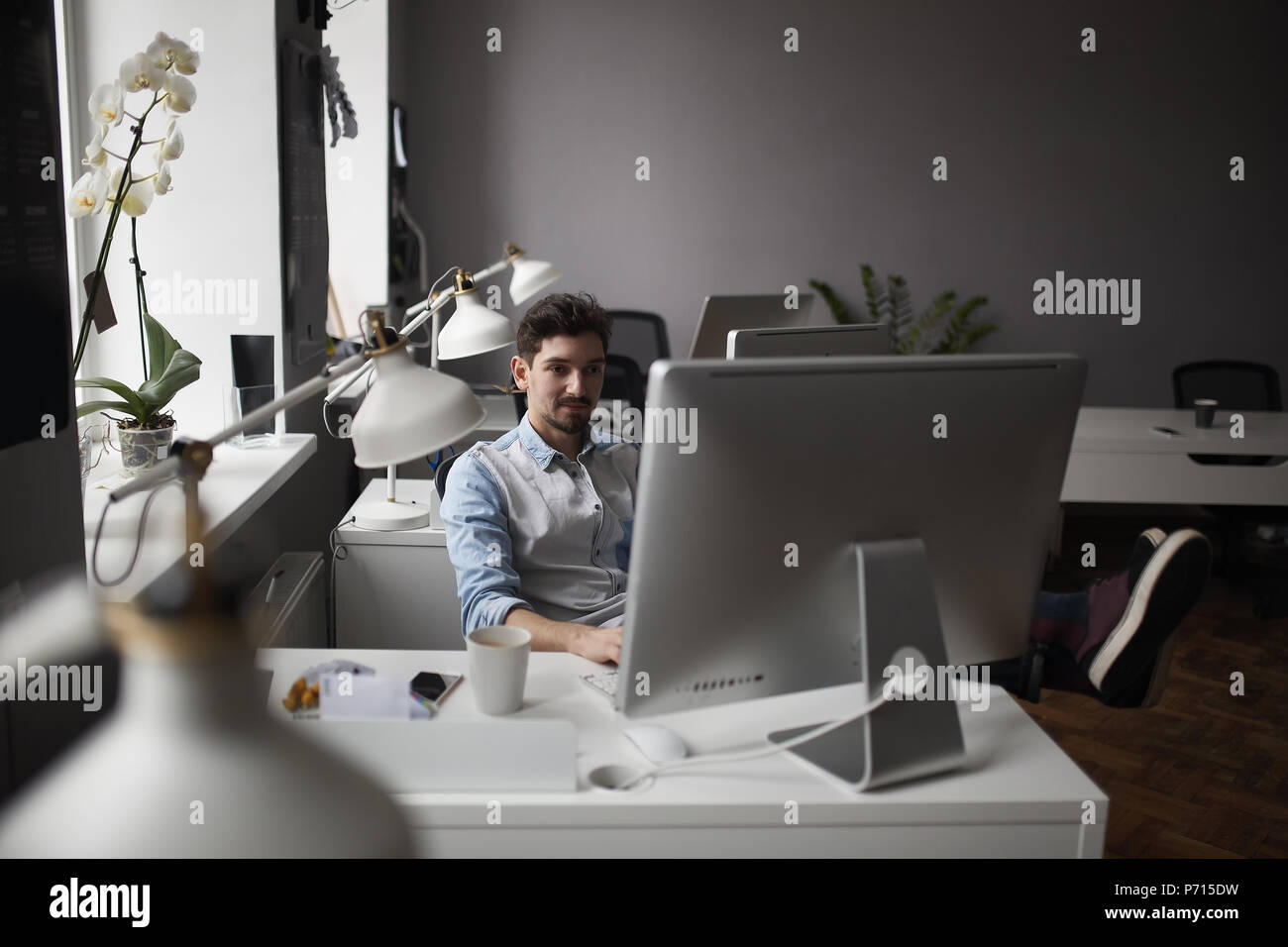 Young intelligent bearded man working at modern loft studio-offi Stock Photo