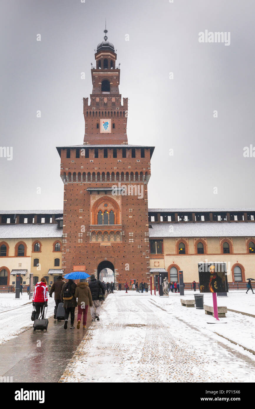 Tourist walks in the courtyard of Sforza Castle during a snowfall, Milan, Lombardy, Northern Italy, Italy, Europe Stock Photo