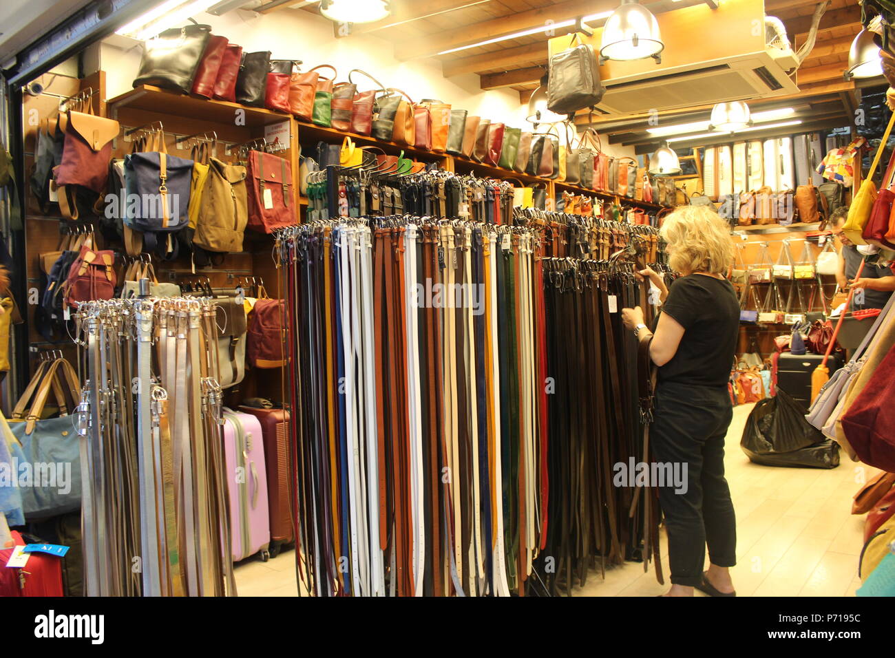 a woman looking at belts in an indoor market stall athens greece Stock Photo