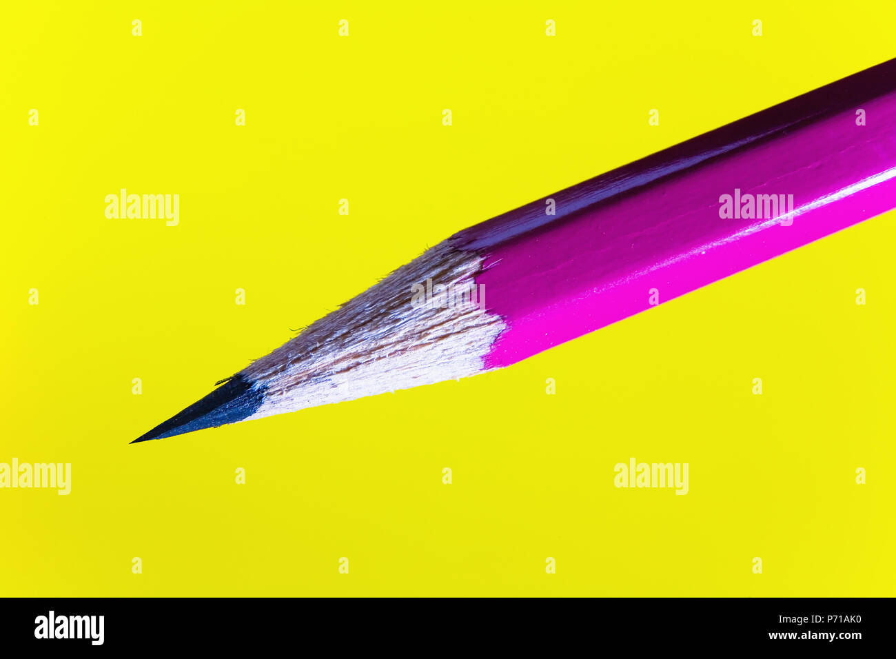 Cheap sharp sharpened pencil on a yellow background. Closeup. Stock Photo