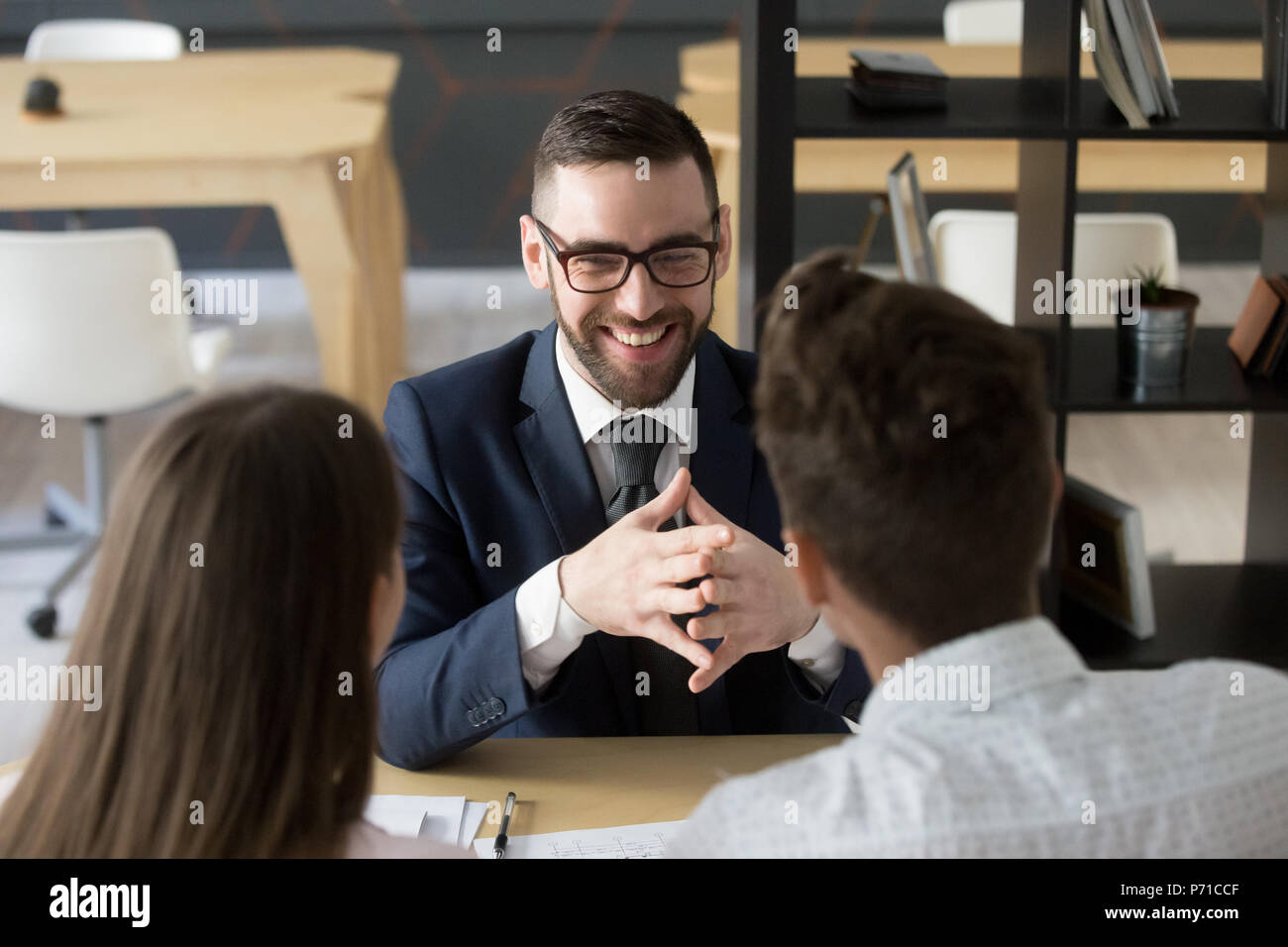 Smiling broker laughing consulting clients in office Stock Photo