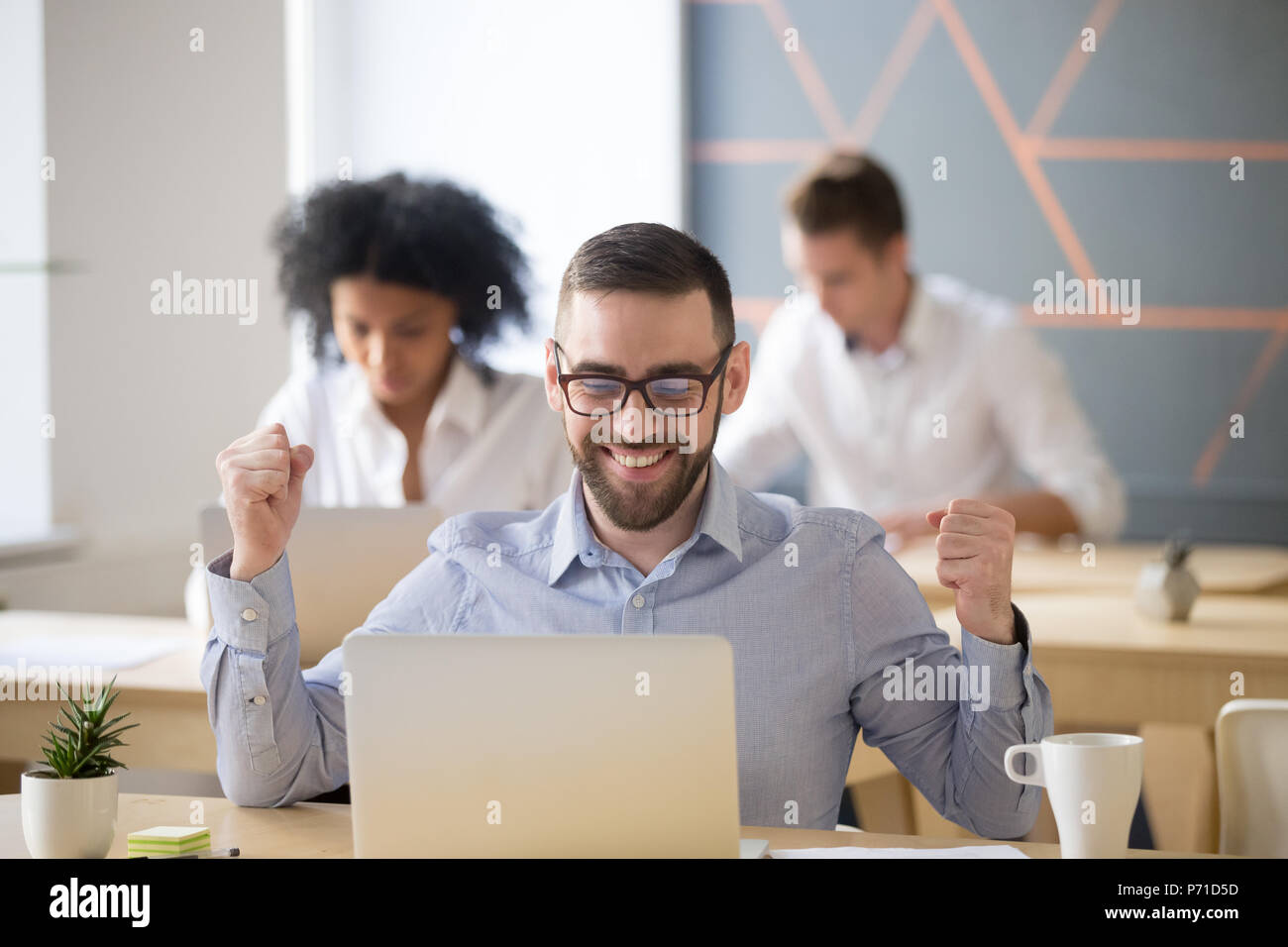Excited male worker winning online lottery sitting in coworking  Stock Photo