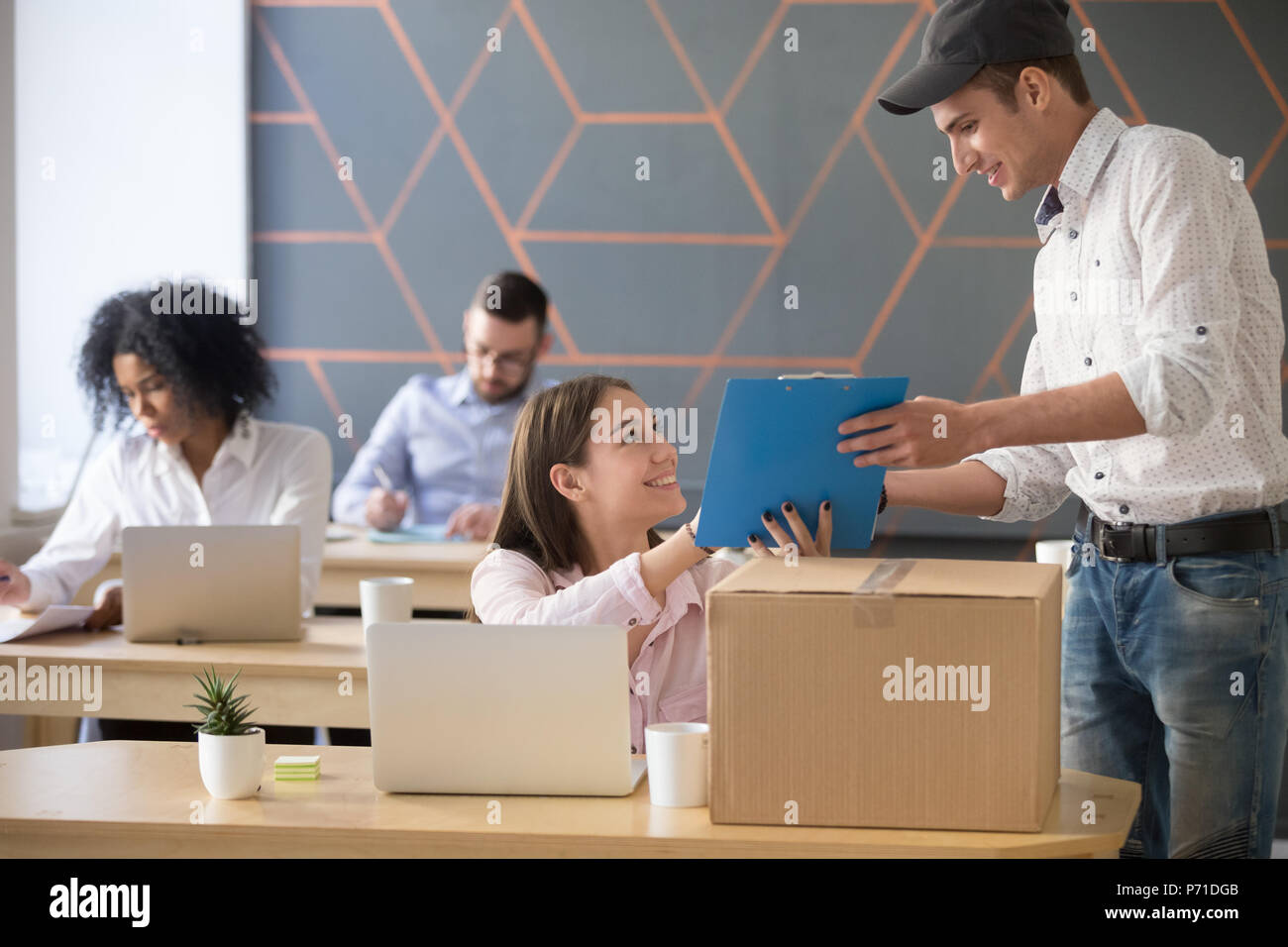 Deliveryman asking woman sign documents after package delivery i Stock Photo