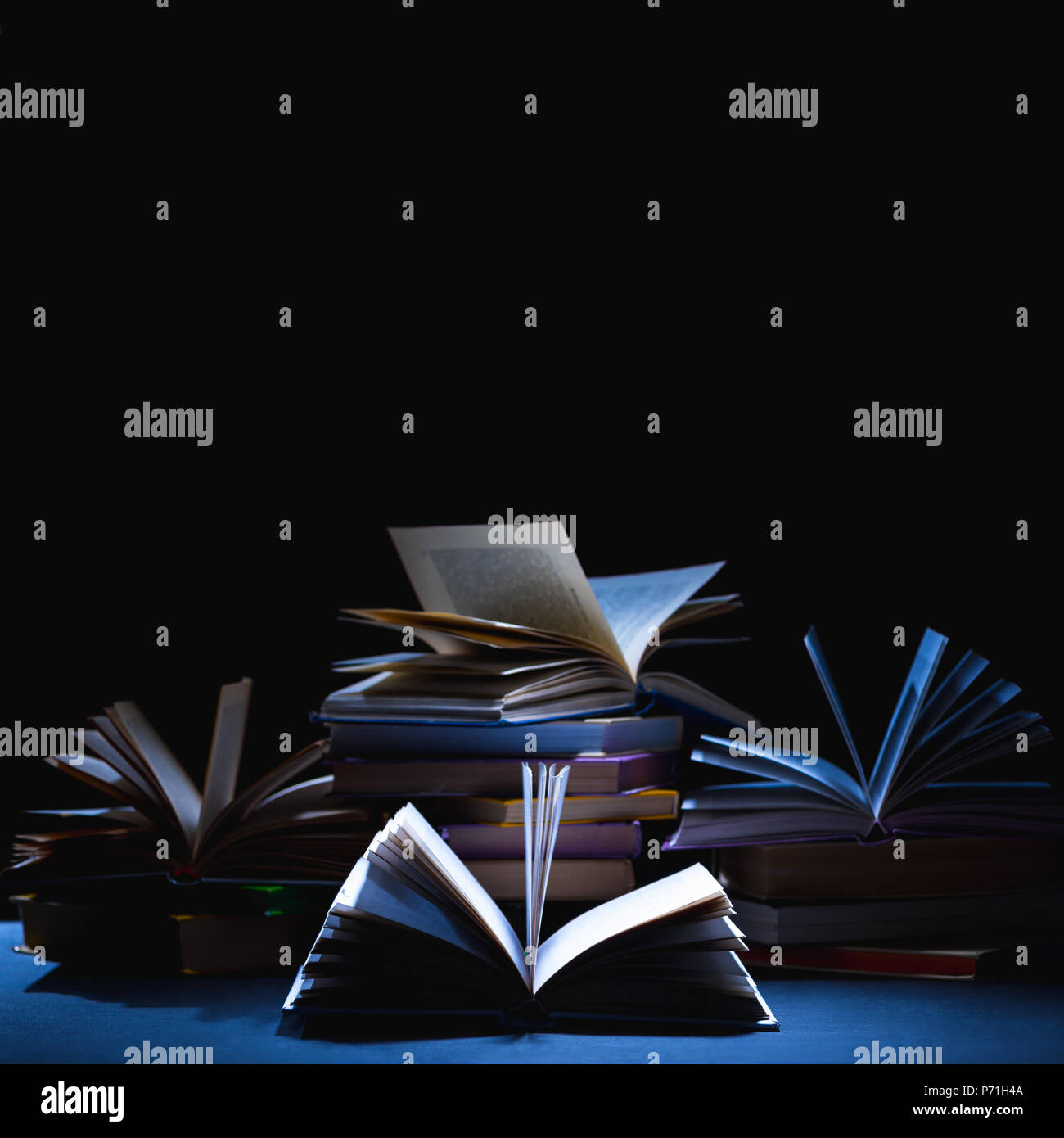 stack of different books on dark tabletop on black Stock Photo