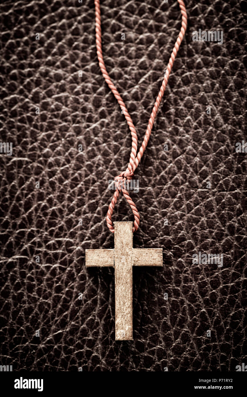 Closeup of simple wooden Christian cross necklace on leather bound holy Bible Stock Photo