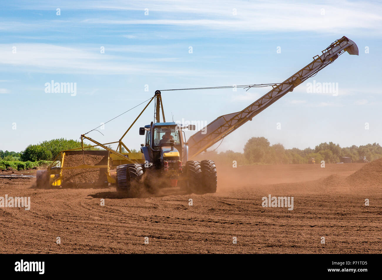Agricultural tractor with harvester stockpiling loose milled peat