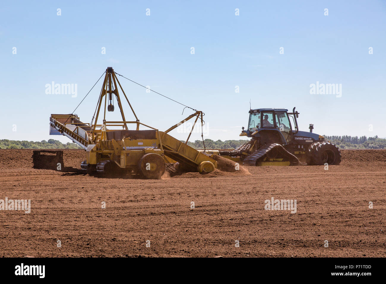 Agricultural tractor with harvester stockpiling loose milled peat