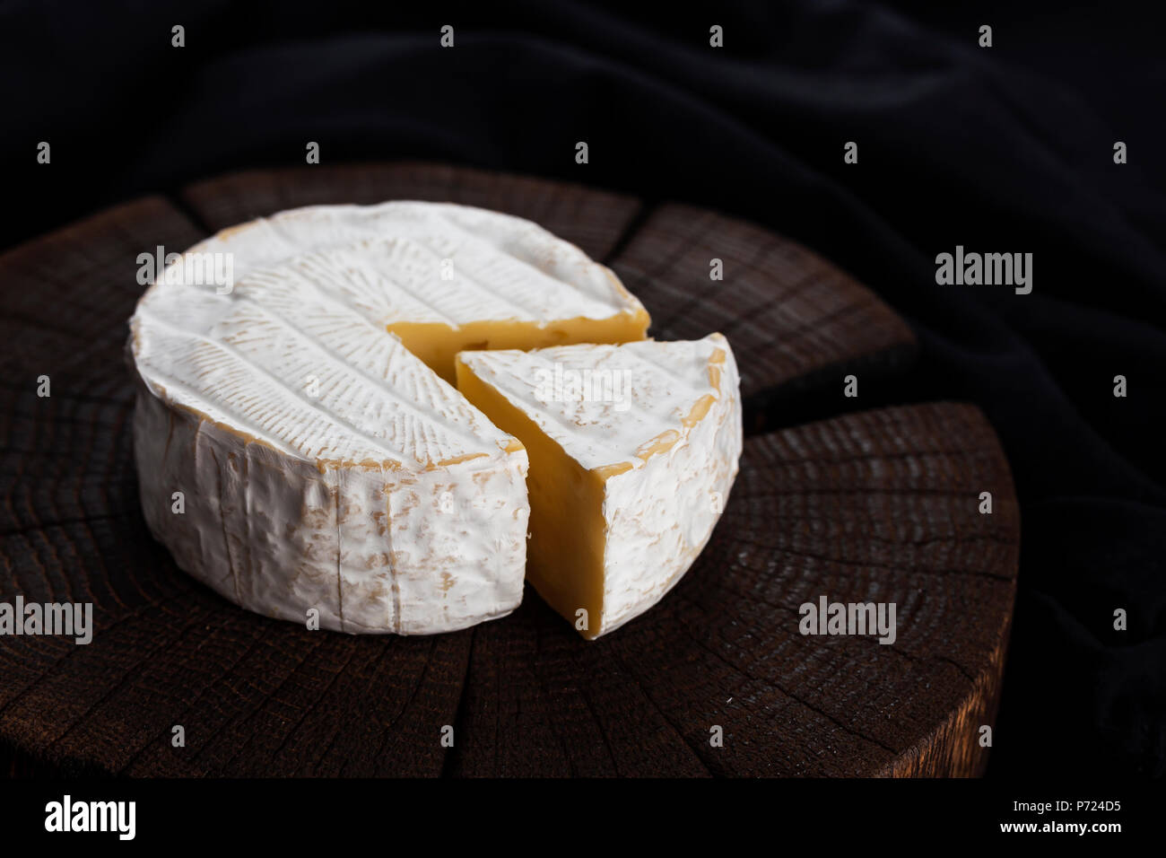 Camembert cheese on black wooden background, with copy space. Shallow depth of field Stock Photo