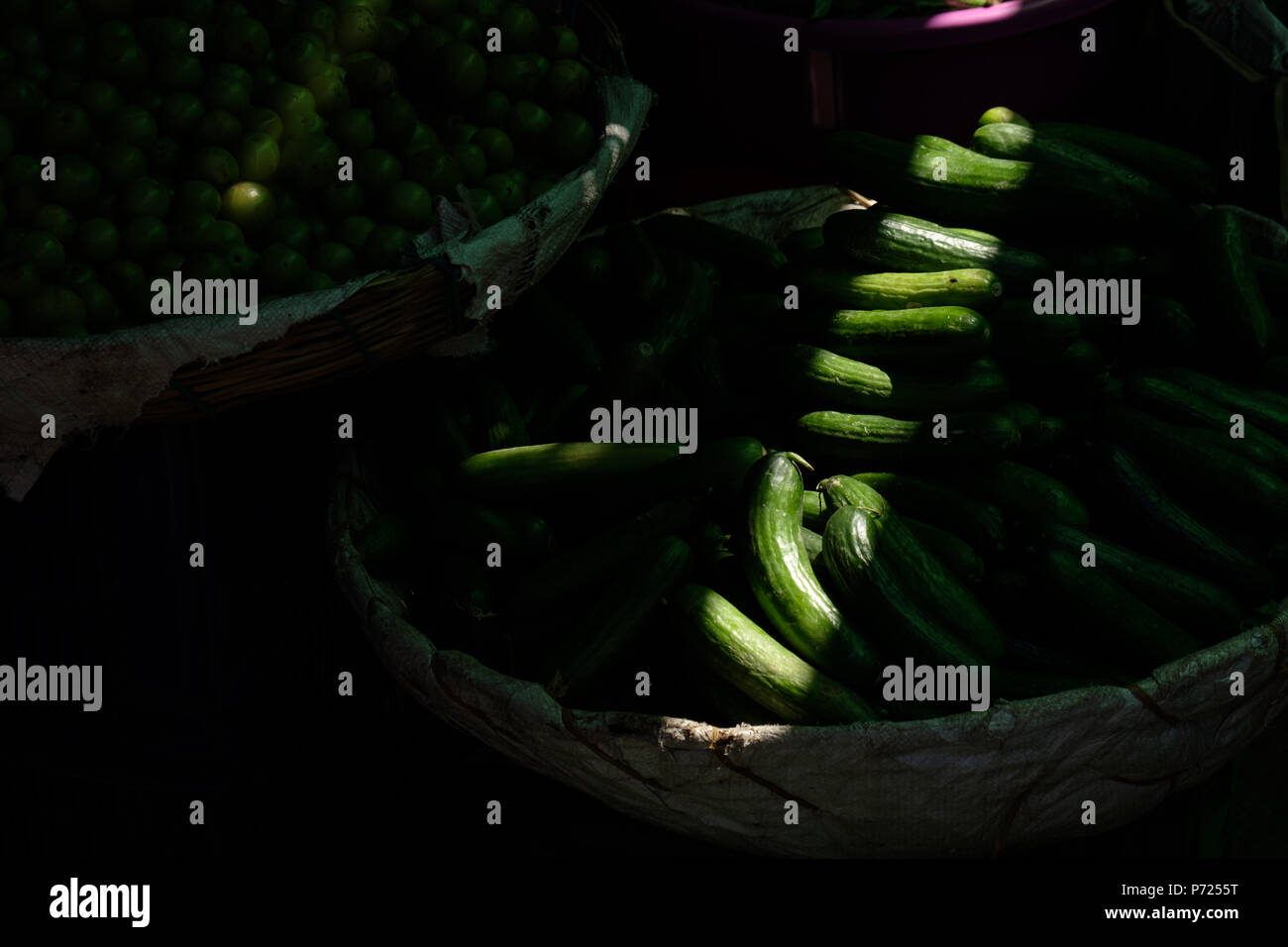 Fresh indian green kakdi cuccumbers lying on market stall, low key Stock Photo